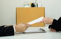 Desperately fired female office worker employee hands her employer her resignation letter and packs her belongings in a cardboard