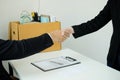 Desperately fired female office worker employee hands her employer her resignation letter, packs her belongings in a cardboard box