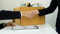 Desperately fired female office worker employee hands her employer her resignation letter, packs her belongings in a cardboard box