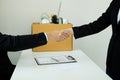 Desperately fired female office worker employee hands her employer her resignation letter, packs her belongings in a cardboard box