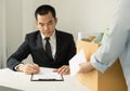 Desperately fired female office worker employee hands her employer her resignation letter and packs her belongings in a cardboard