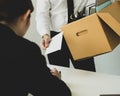 Desperately fired man office worker employee hands her employer her resignation letter and packs her belongings in a cardboard box