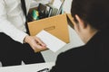 Desperately fired man office worker employee hands her employer her resignation letter and packs her belongings in a cardboard box
