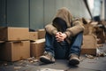 A despondent man conceals his face while sitting on a cardboard, expressing hopelessness