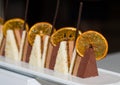 Dessert. Cake slices made of white sponge cake crust and brown chocolate mousse and a slice of caramelized orange and a stick of