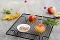 Dessert, caramelized candy apples in transparent caramel, sprinkled with sugar decor, on a black grate on a gray concrete Royalty Free Stock Photo