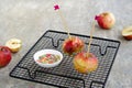 Dessert, caramelized candy apples in transparent caramel, sprinkled with sugar decor, on a black grate on a gray concrete Royalty Free Stock Photo