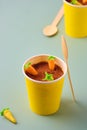 Dessert, carrot cake to go in a yellow paper cup, decorated with cocoa and marzipan carrots on a green plain background. Trendy Royalty Free Stock Photo