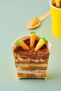 Dessert, carrot cake to go in a yellow paper cup, decorated with cocoa and marzipan carrots on a green plain background. Trendy Royalty Free Stock Photo