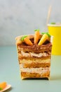 Dessert, carrot cake to go in a yellow paper cup, decorated with cocoa and marzipan carrots on a green plain background. Trendy Royalty Free Stock Photo