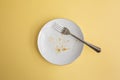 Dessert crumbs in round plate with fork on yellow background Royalty Free Stock Photo