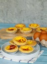 Egg tart or Portugal egg tart sweet custard cream on white dish and blue wooden table with eggs ingredients
