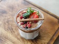 Dessert in a glass, decorated with a cinnamon stick, slices of berries and mint leaves