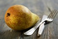 Dessert knife, fork and ripe pear.