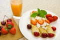 Dessert made from pancakes stuffed with curd cheese with strawberries and cherries is on a table in a white plate Royalty Free Stock Photo