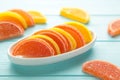 Dessert marmalade in the form of lemon and orange slices in plate on blue background