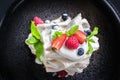 Dessert Pavlova with strawberry, raspberry, mint, bilberry on a grey background. Top view Royalty Free Stock Photo