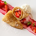 A dessert plate with crepes, strawberry fruits, whipped cream and mint