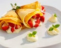 A dessert plate with pancakes, strawberry fruits, whipped cream and mint