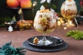 Dessert, portioned apple trifle with oat crumble, spiced cake, custard and whipped cream in a glass glass in a Christmas style