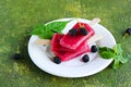 Dessert, portioned homemade ice cream or popsicles made from red currants and blackberries on a white plate against a green