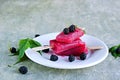Dessert, portioned homemade ice cream or popsicles made from red currants and blackberries on a white plate on a gray concrete