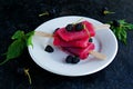 Dessert, portioned homemade ice cream or popsicles made from red currants and blackberries on a white plate on a gray concrete