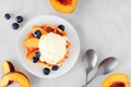 Dessert waffle with vanilla ice cream, peaches and blueberries, overhead table scene on a white marble background Royalty Free Stock Photo