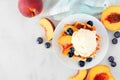 Dessert waffle with vanilla ice cream, peaches and blueberries, top view table scene over a white marble background. Royalty Free Stock Photo