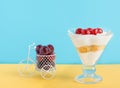 A dessert from whipped cream, ice cream and biscuits and a small bicycle with maraschino cherry in a glass .
