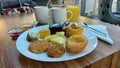 Oriental small cakes on a white plate. Marmalade in glass bowls. Coffee and juice.