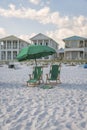 Destin, Florida- Green outdoor lounge chairs under the umbrella on a white beach sand Royalty Free Stock Photo