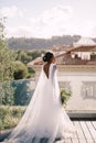 Destination fine-art wedding in Florence, Italy. African-American bride, with a bouquet in her hands, stands on the roof