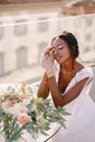 Destination fine-art wedding in Florence, Italy. African-American bride sits at the table, touches her face with gloves