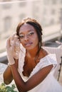 Destination fine-art wedding in Florence, Italy. African-American bride sits at the table, touches her face with gloves