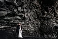 Destination Iceland wedding. Wedding couple under a rock of basalt stones. Bride and groom on the black beach of Vik. Royalty Free Stock Photo