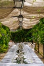 Destination wedding dinner set up under a pergola and wisteria. Royalty Free Stock Photo