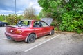 Destroyed abandoned car with broken car glasses, flat tires and open hood