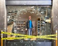 Destroyed boutique showcase broken on pieces of glass, crime tape beside and mannequin behind, concept of vandalism. Royalty Free Stock Photo