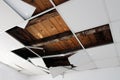 Destroyed broken white ceiling tiles with visible wooden boards above at abandoned military building