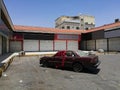 Destroyed car abandoned in front of closed shops, Saudi Arabia