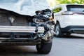 Destroyed car in car crash traffic accident on city road. Smashed broken front auto headlight, dented hood no bumper on gray SUV Royalty Free Stock Photo