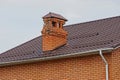 Destroyed chimney pipe made of brown brick on the tiled roof Royalty Free Stock Photo