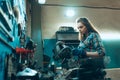 Destroying gender stereotypes. Young woman auto mechanic working at auto service station using different work tools