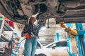 Destroying gender stereotypes. Young woman auto mechanic working at auto service station using different work tools