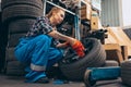 Destroying gender stereotypes. Young woman auto mechanic working at auto service station using different work tools Royalty Free Stock Photo