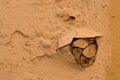 Destruction in the wall. Cracks in plaster and hole formed after a strong penetrating blow from that inner side of wall with an