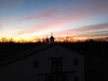 Detached house and the silhouette of horse weathervanes,trees against orange-red sky at the sunset