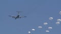 A detachment of military soldiers parachutists jump out of the plane and go down against the blue sky