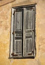 Detail of an abanondoned house .Old wooden closed window on yellow wall Royalty Free Stock Photo